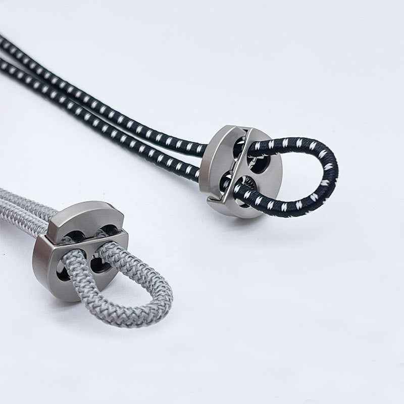 Silver cord lock with braided drawstring threaded through two holes, adjustable clasp