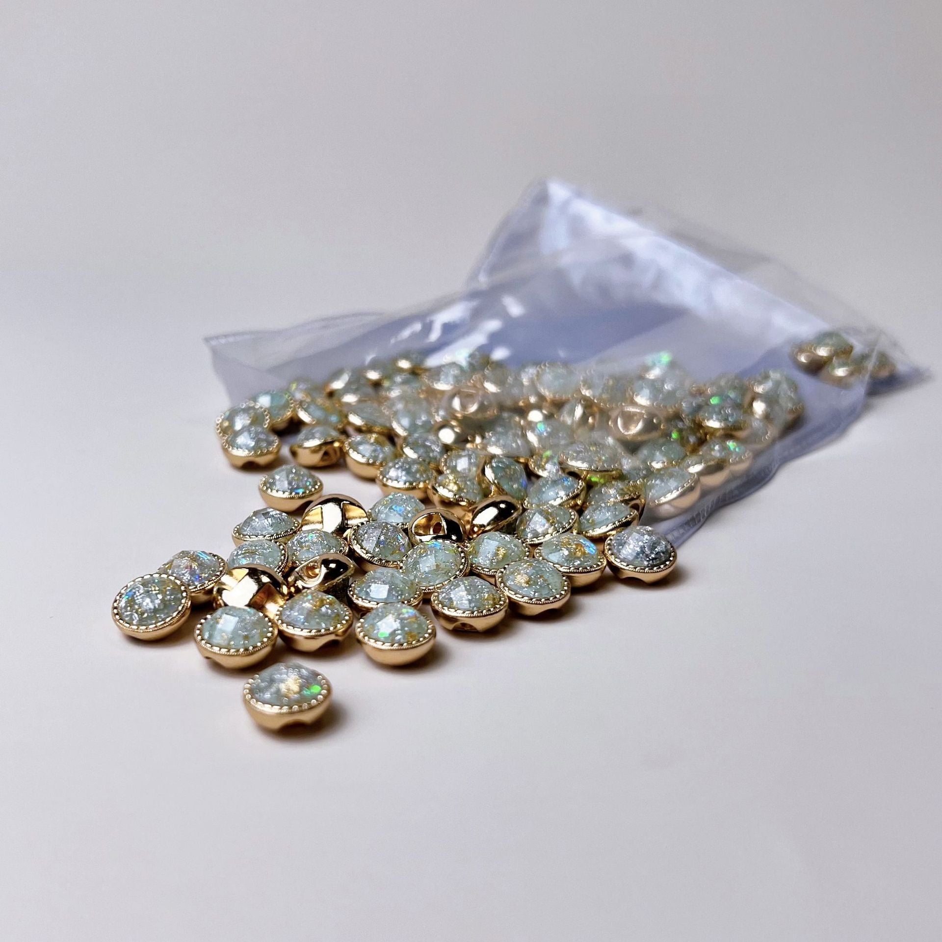 Beutel mit Metallhemdknöpfen 10mm, goldfarbene Fassungen und blau-grün irisierendem Stein