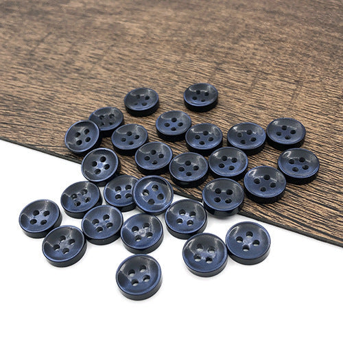 Navy blue round 4-hole shirt buttons, stacked and scattered on board