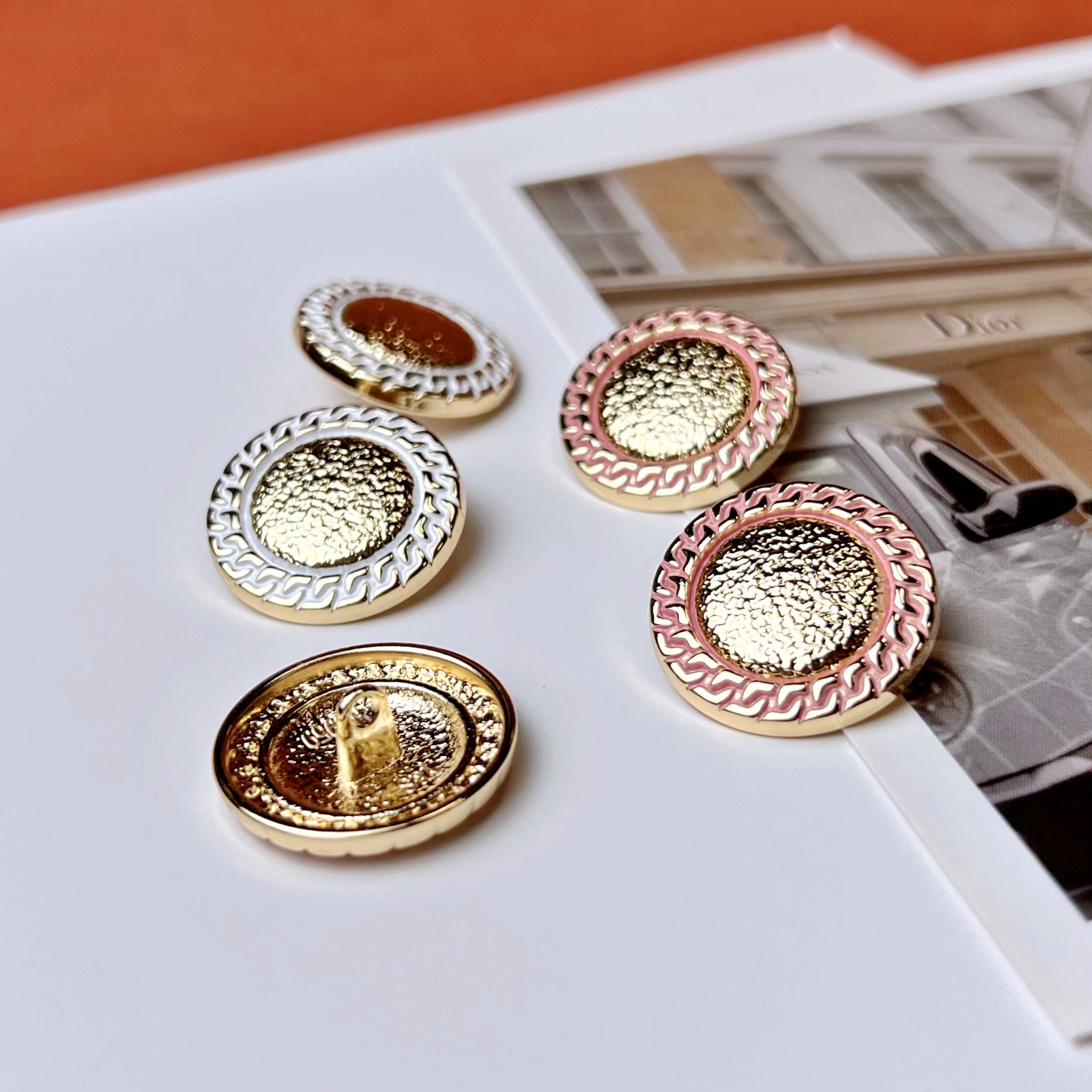 Assorted gold-center metal buttons with black, white, and pink chain-edge details