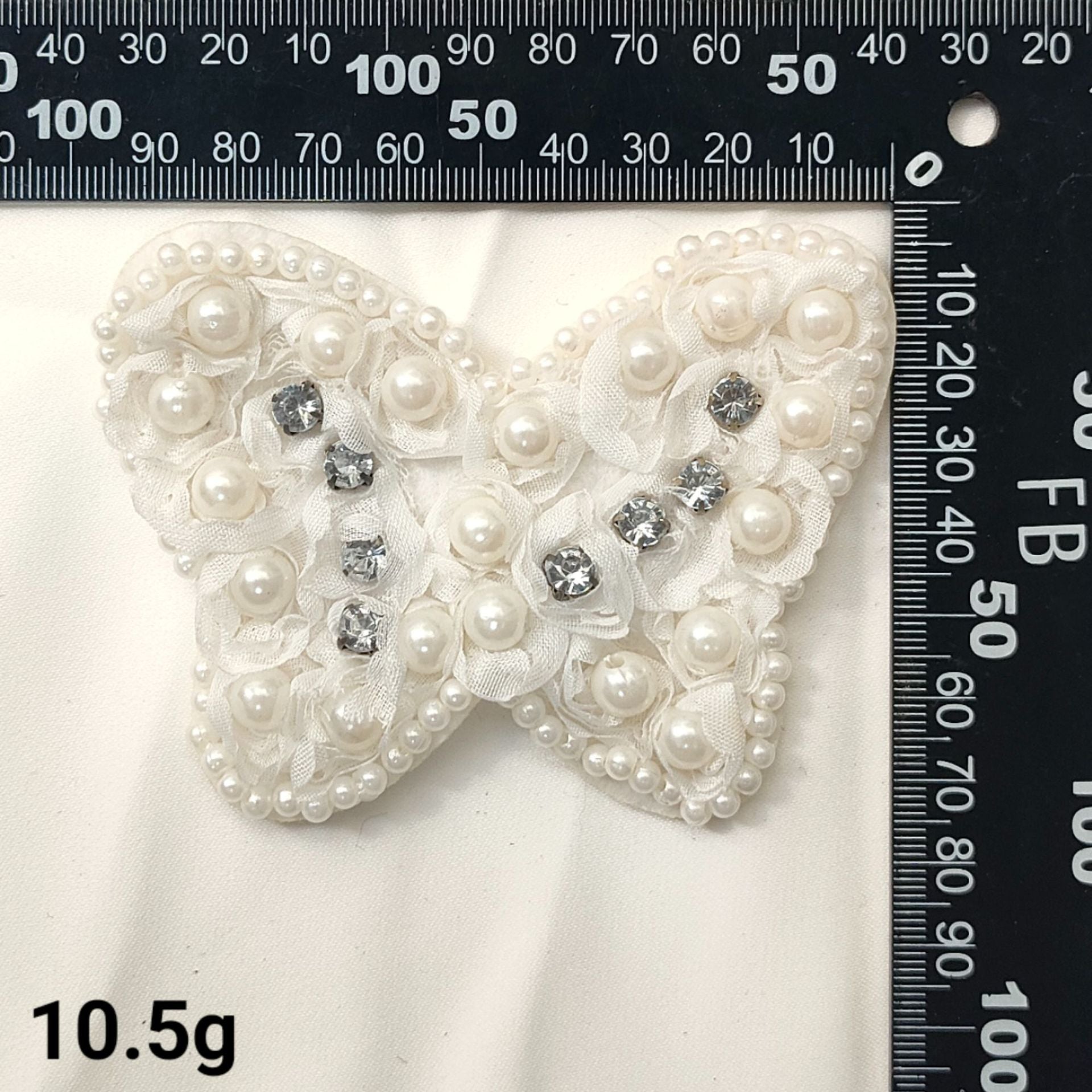 White pearl and rhinestone bow patch with small gem accents and layered petals
