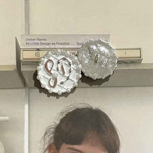 Ronde knoop met parelrand, glanzende metalen ondergrond en wit/zwart patroon