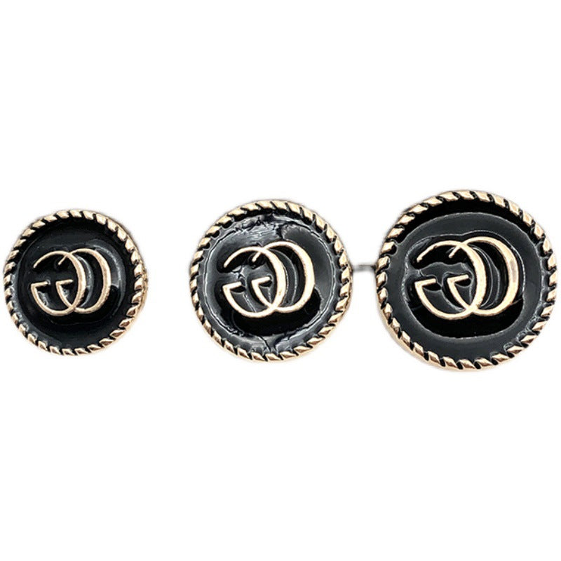 Runde schwarze G-Logo-Knöpfe mit goldfarbener Ziernaht und metallischer Optik