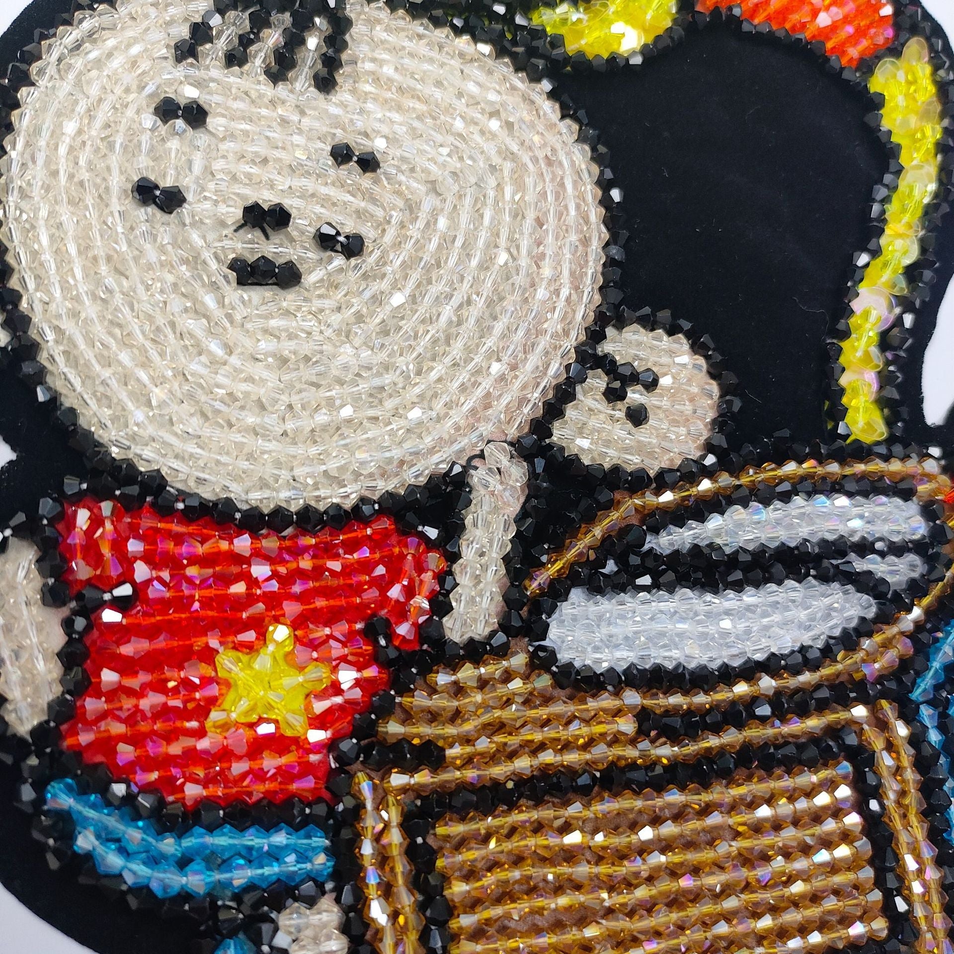 Nahaufnahme der Strass- und Perlenstickerei der Shinchan-Applikation in Schwarz, Weiß, Rot