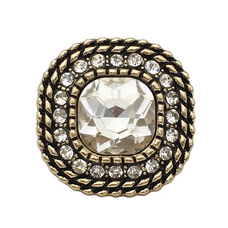 Close-up vintage square metal shank button with clear white crystal center and gold rhinestones