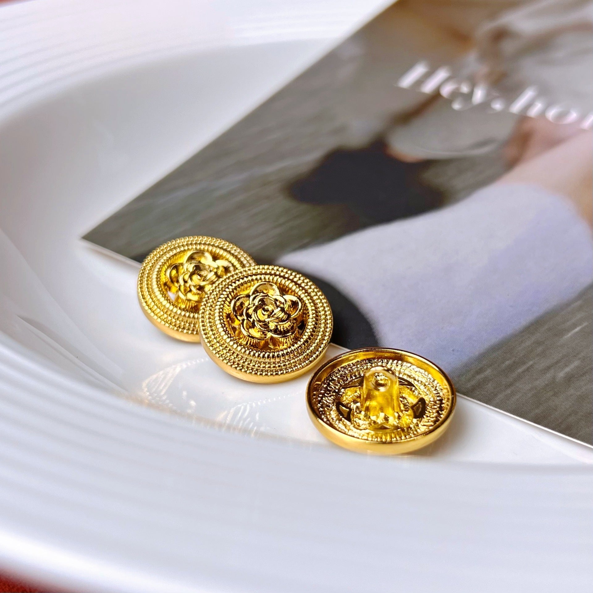 Two gold metal shank buttons with filigree rose motif and braided edge