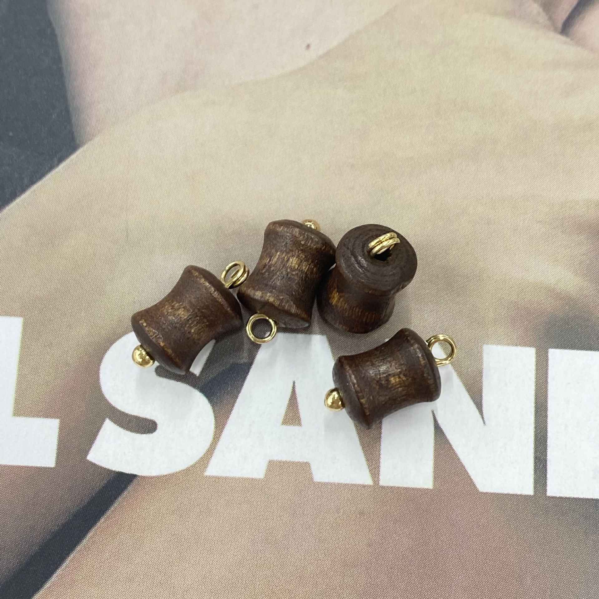 Brown wooden cylinder buttons with concave end and gold loop fasteners