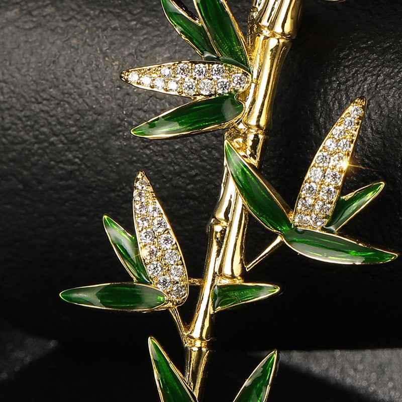 Gold bamboo brooch with green enamel leaves and sparkling crystal-like accents