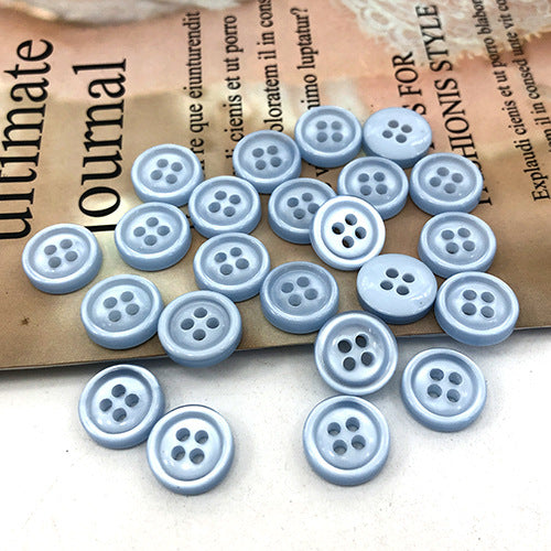 Light blue round 4-hole shirt buttons, assorted quantity in a pile