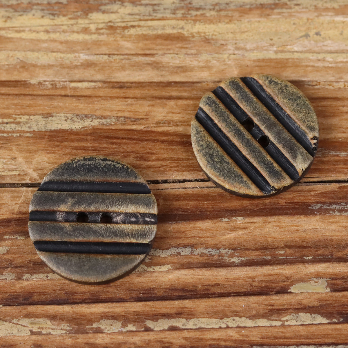 Grooved round button pair with two holes, black striped ridges detail