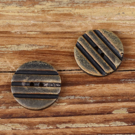 Grooved round button pair with two holes, black striped ridges detail