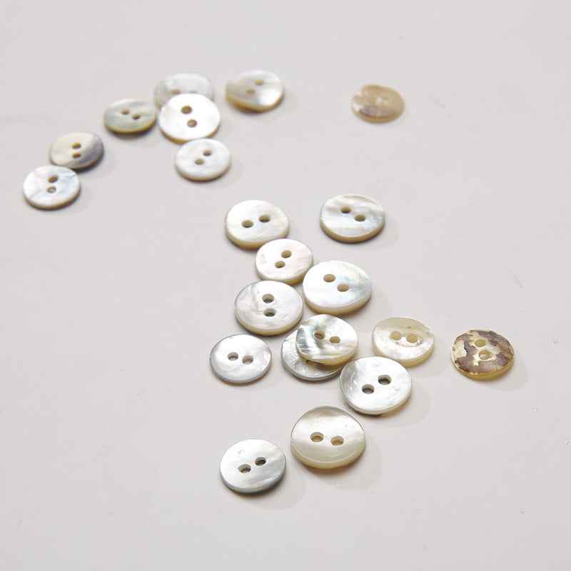 2-hole round mother-of-pearl buttons in mixed off-white and pale gold tones, iridescent surface
