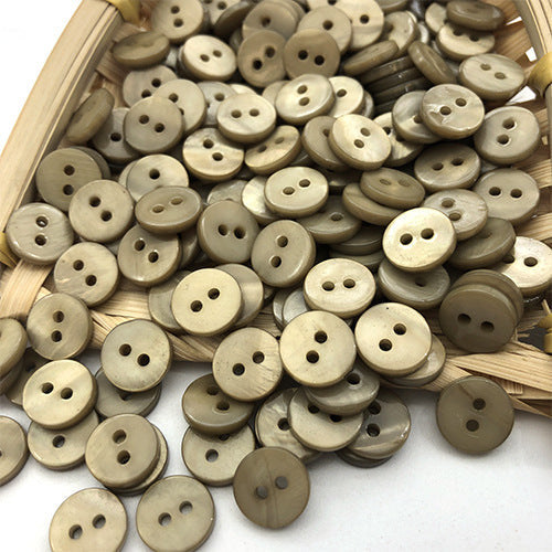 Beige und olivefarbene runde 2‑Loch Shirtknöpfe aus Naturmuschel, in einer Schale