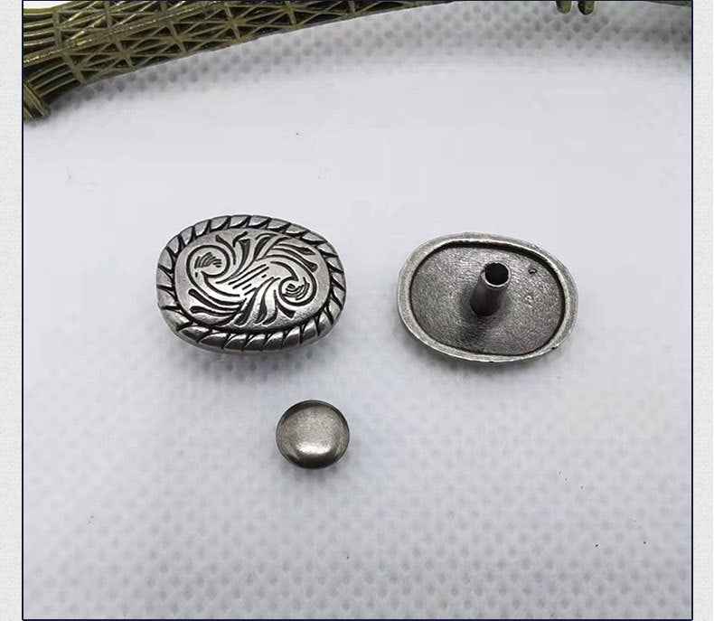 Oval floral scroll rivet stud with metal backing and separate round cap piece.