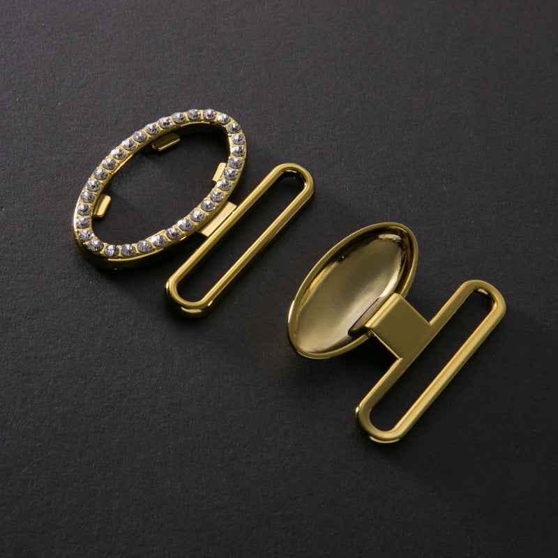 Zwei Buckles mit ovalem Strassbesatz und Metallklammern, goldfarben