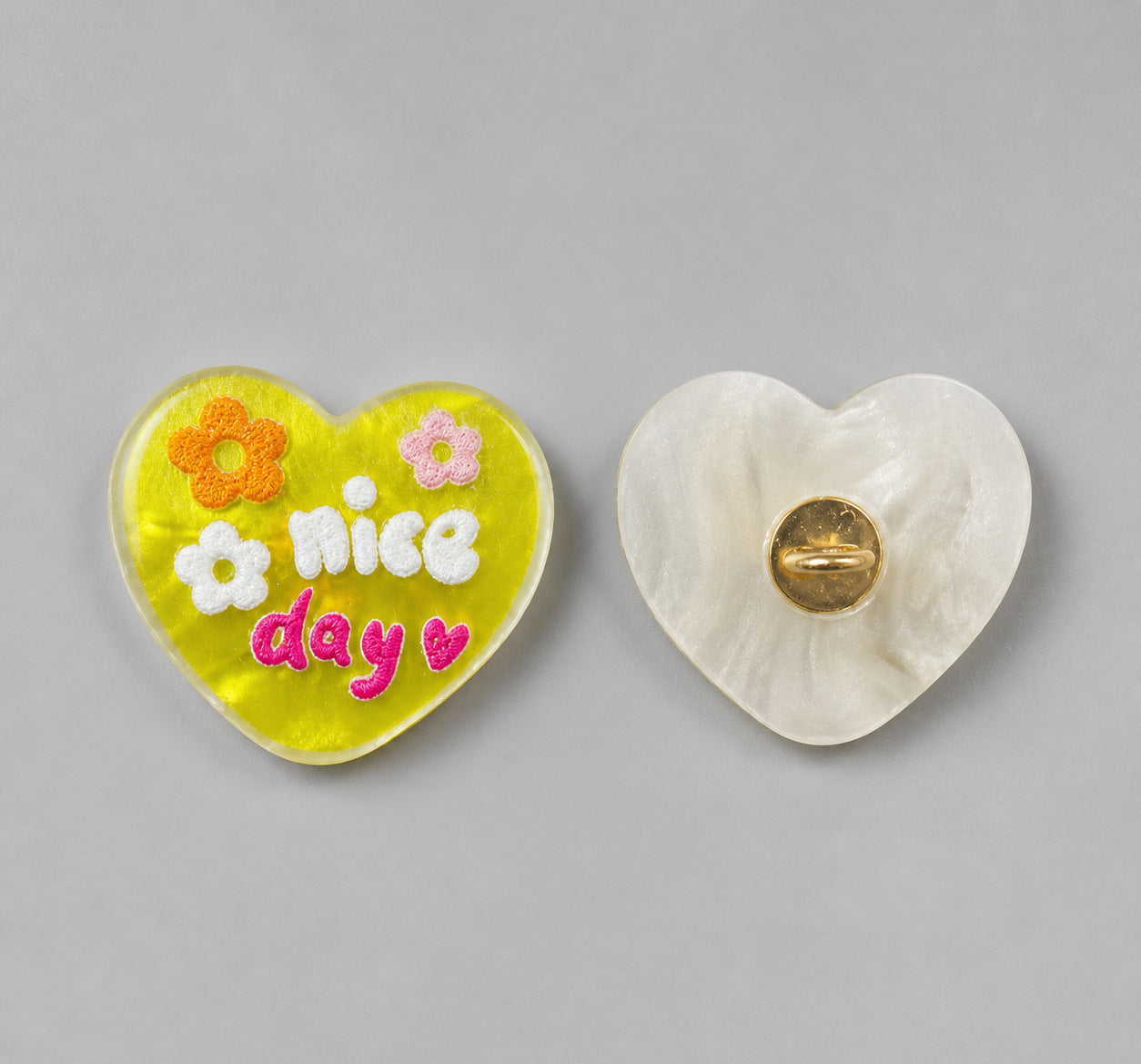 Chartreuse heart-shaped resin button with “nice day” and flowers; white back with gold pin