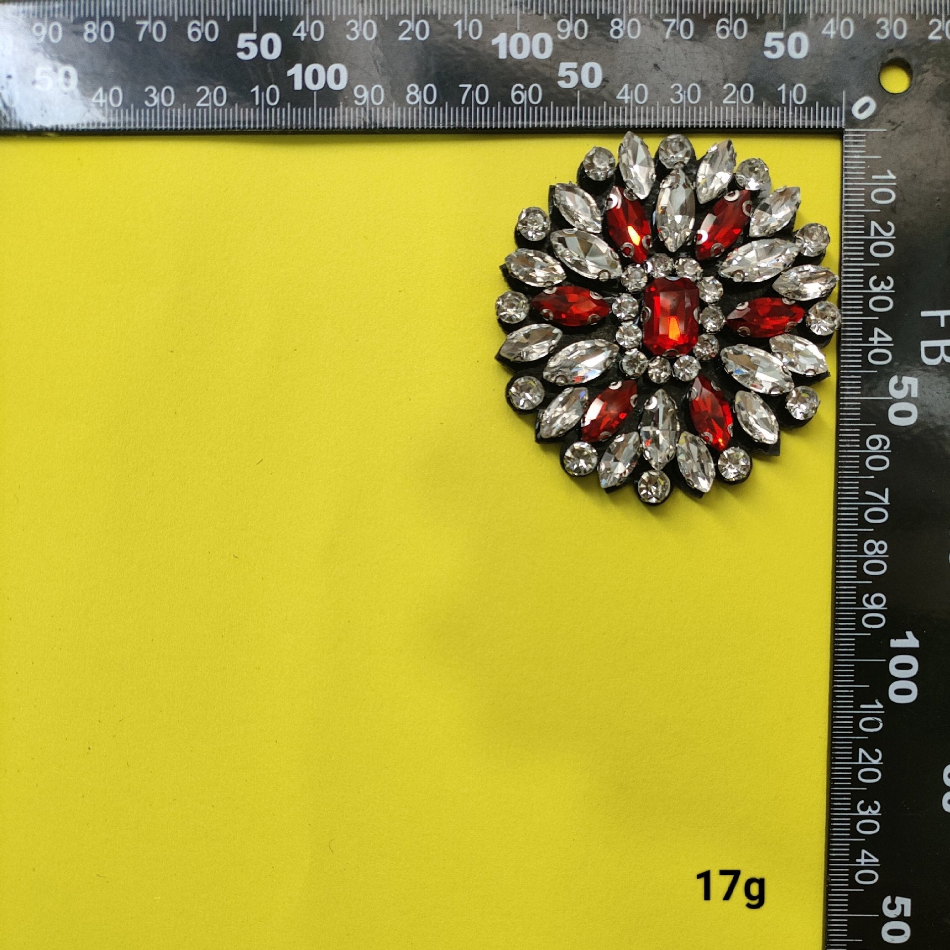 Red and silver rhinestone flower fabric patch with gem center, measured next to ruler