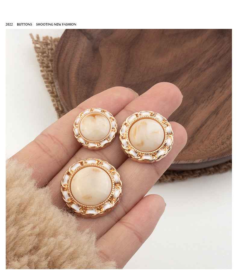 Three beige resin shank buttons with gold-tone ornate frames
