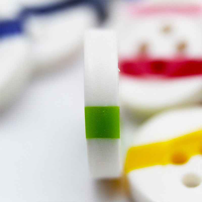 White button close-up with green stripe and partial yellow stripe, four holes visible
