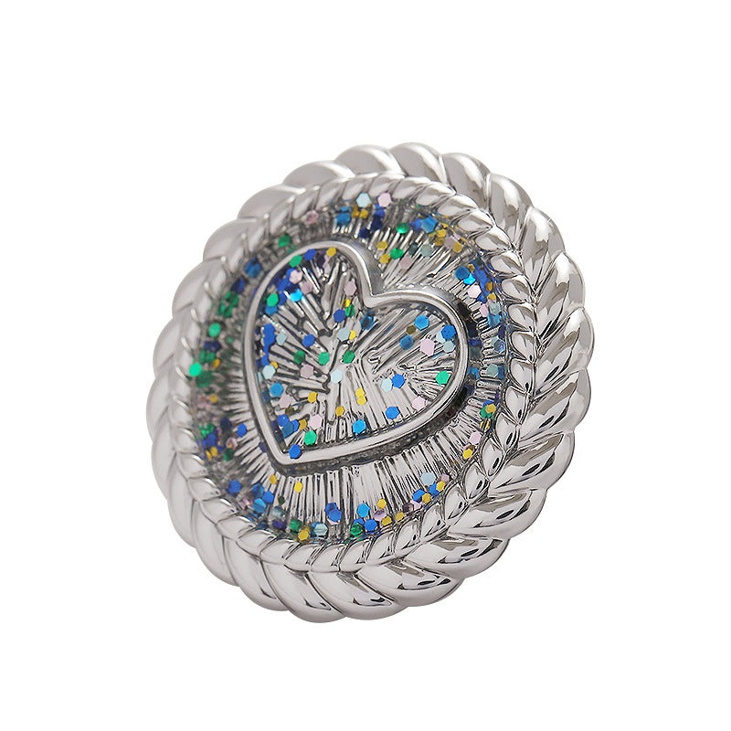 Silver heart-shaped metal shank button with braided rim and blue glitter mosaic center