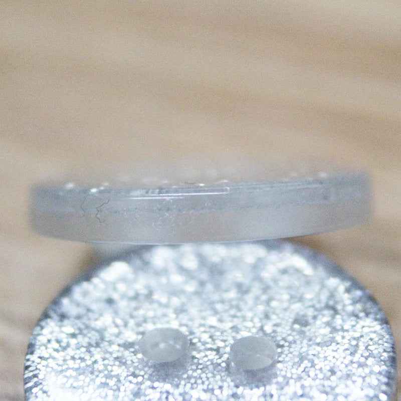 Close-up: white transparent glitter resin button with two holes