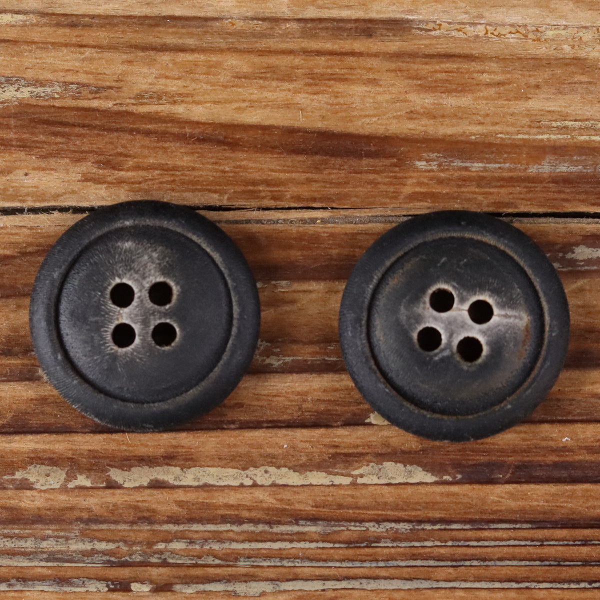 Two dark four-hole buttons with matte surface texture