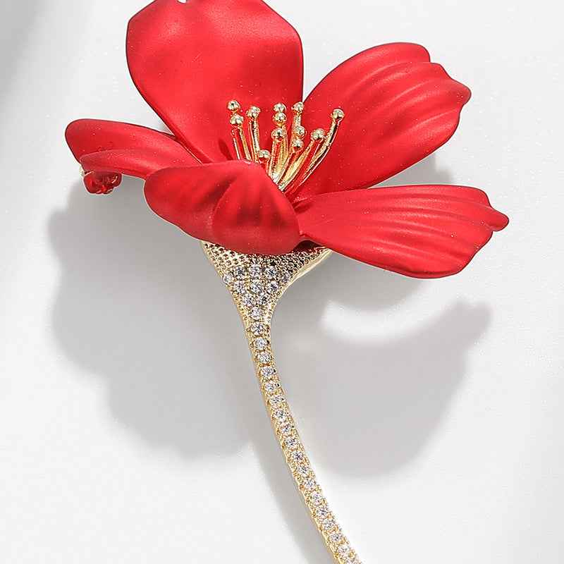 Nahaufnahme: rote Hibiskus-Blüte mit goldfarbenen Stempeln und funkelndem Strass-Stiel