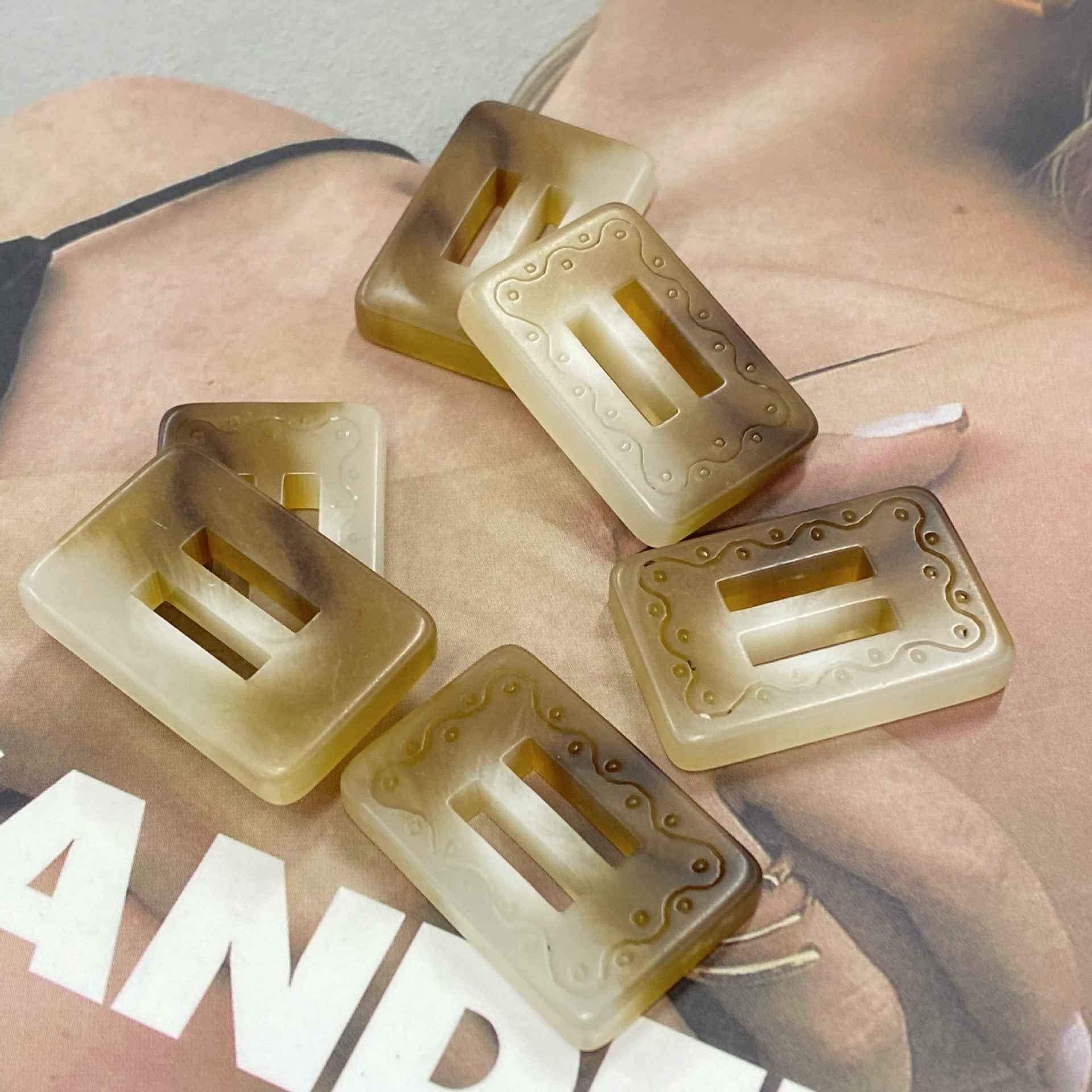 Rectangular resin 2-hole buckle buttons in golden brown, khaki/cream, and light tones