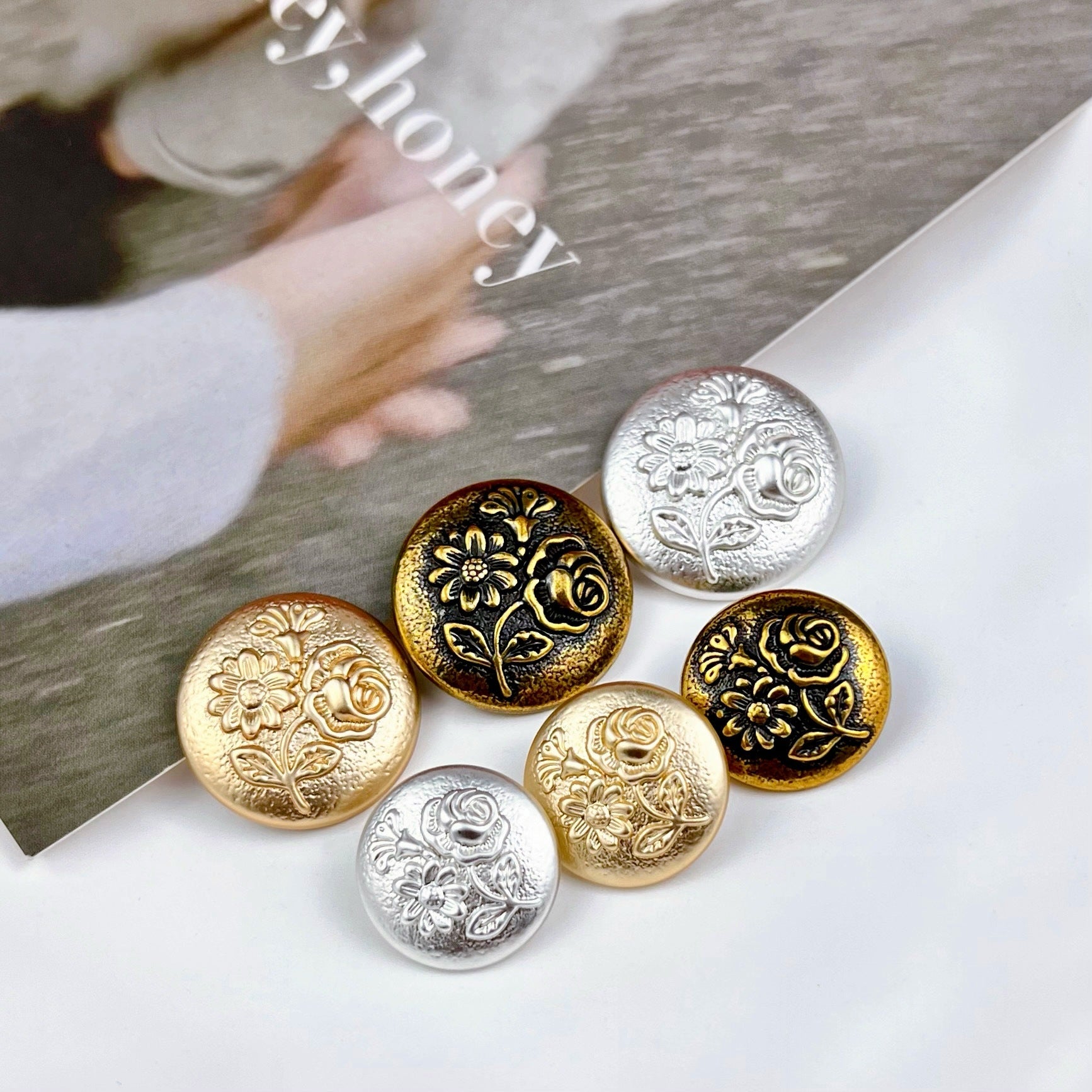Assorted round metal shank buttons with embossed three-flower design, gold/silver/bronze