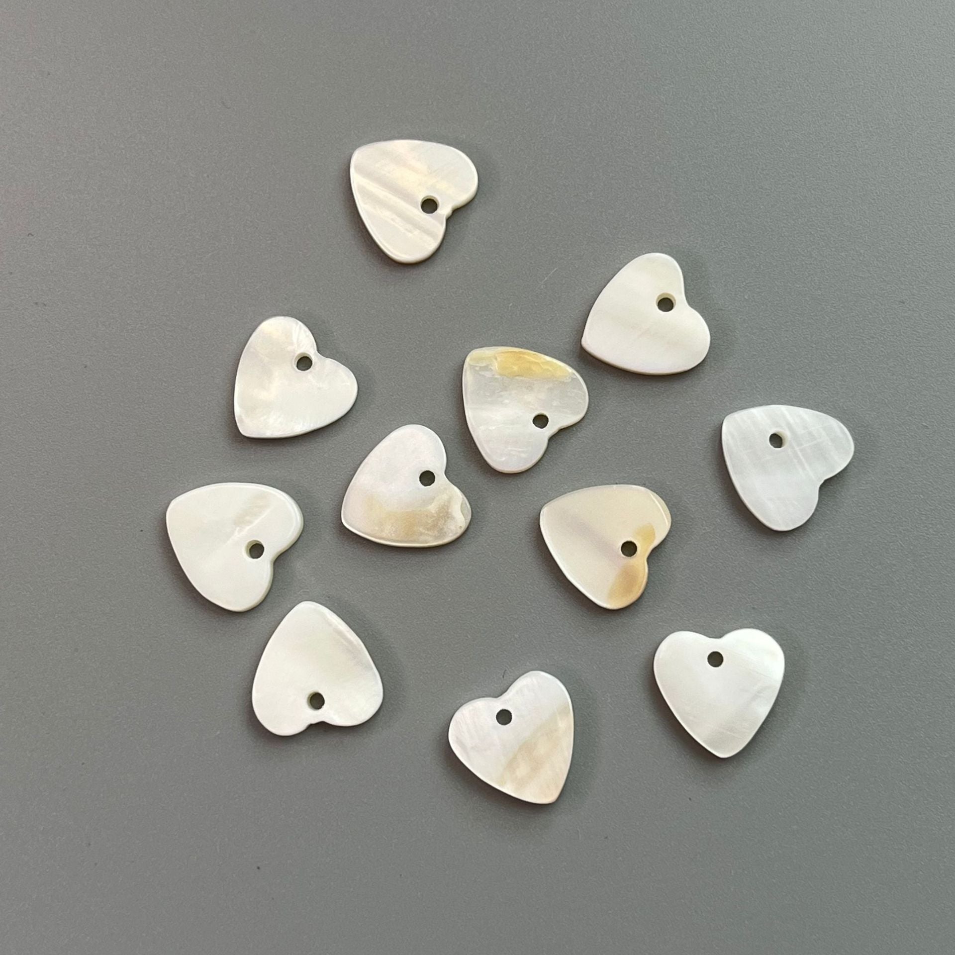 Assorted white heart shell buttons with 2-hole openings, smooth curved faces.