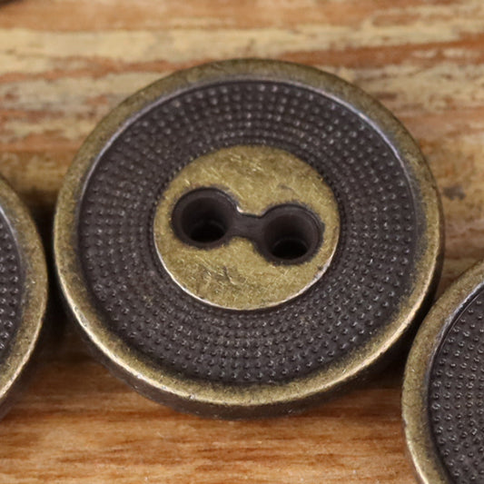 Close-up of a 2-hole metal button with concentric circle border, dark bronze finish