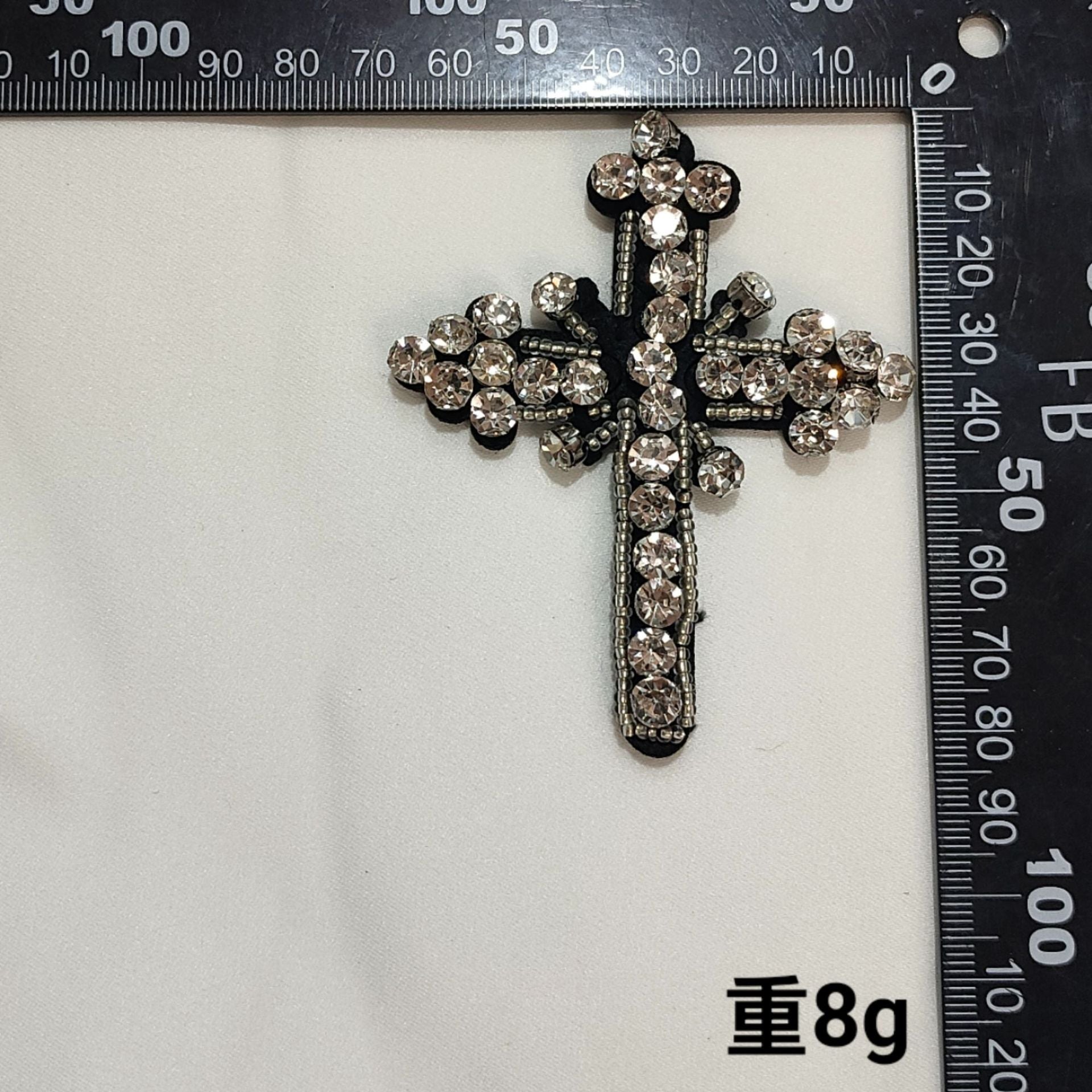 Dark beaded cross badge patch with clear rhinestone clusters and raised edges