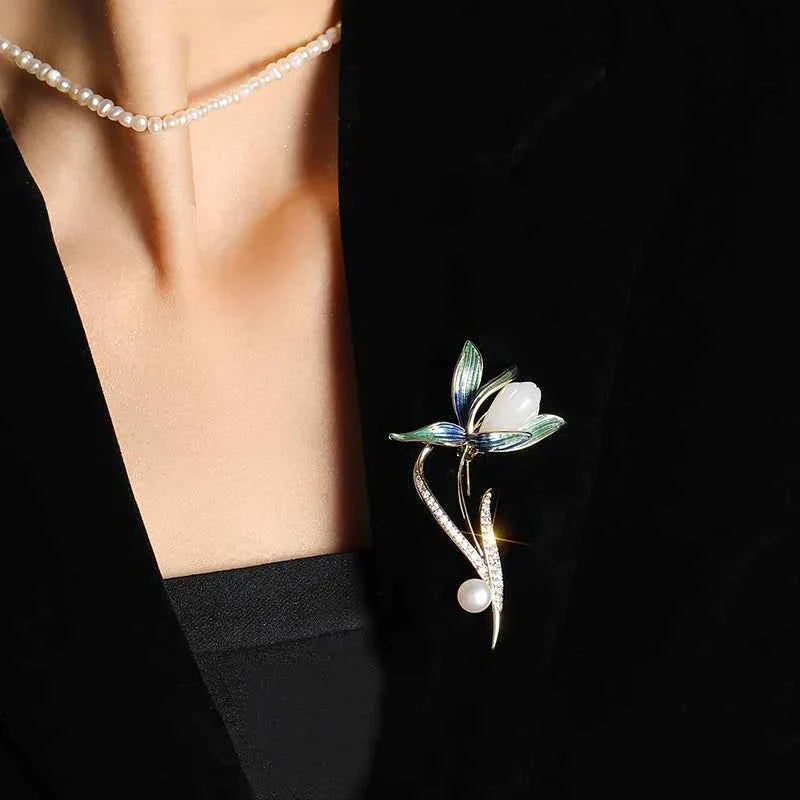 Magnolia brooch pin on clothing, blue-green enamel flower with white pearl drop