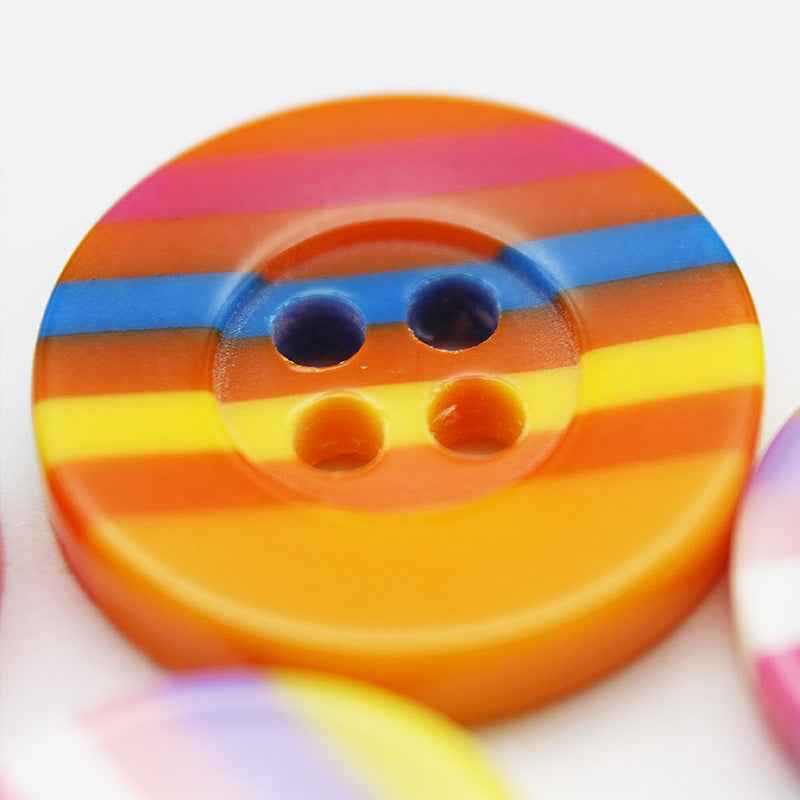Close-up: orange 4-hole resin button with blue and yellow stripes, wide edge