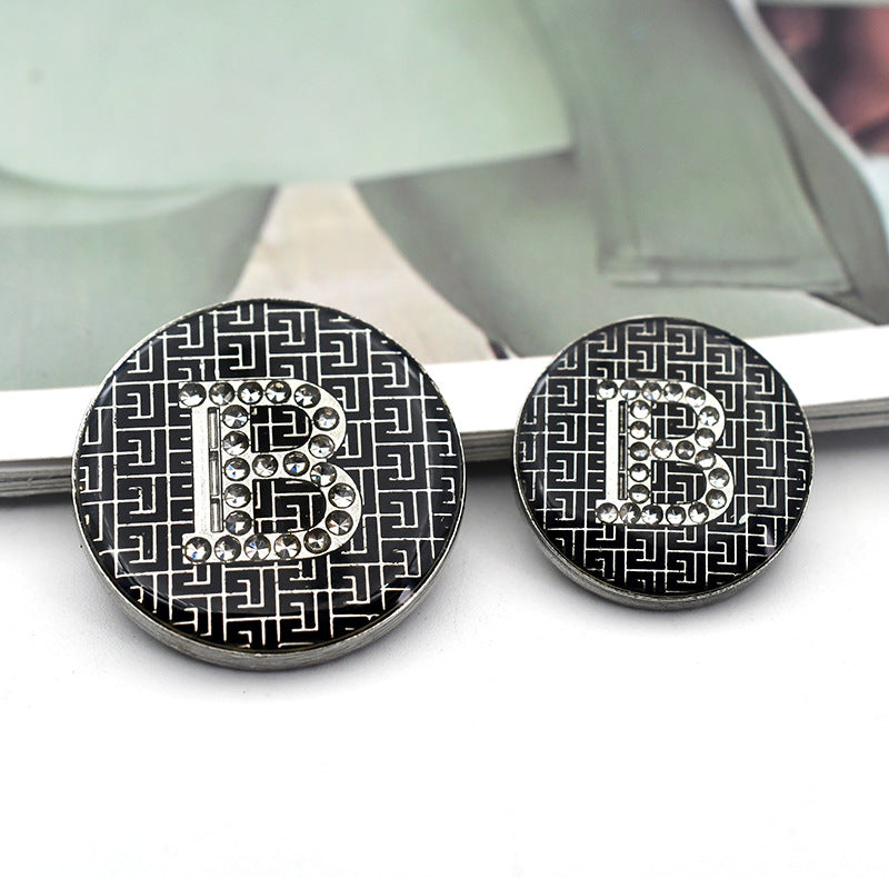 Black round button with rhinestone letter 'B' and geometric pattern border