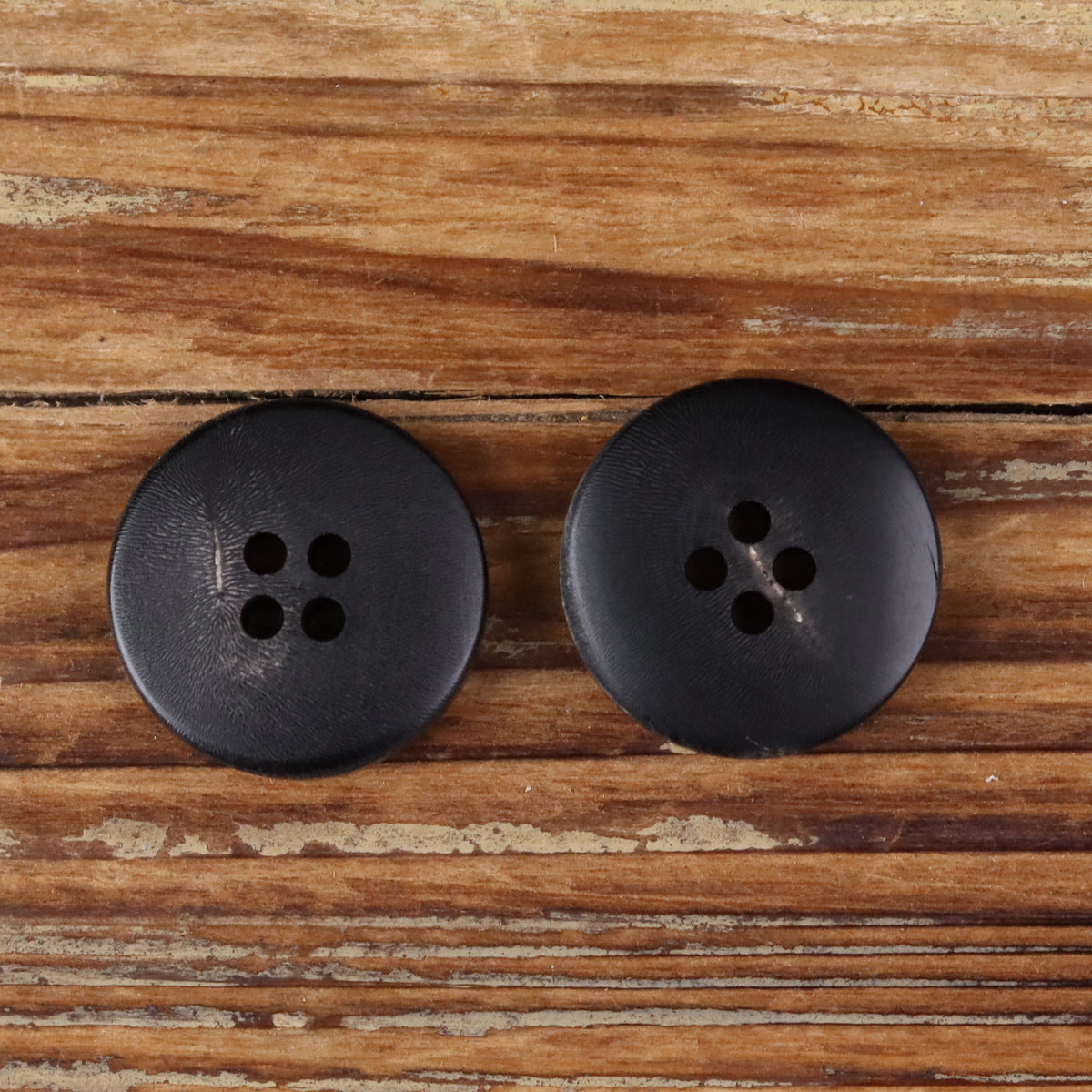 Pair of round four-hole buttons in dark black tone