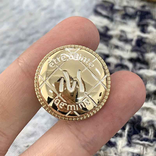 Gold round metal button with engraved M and cross lines, beaded rim