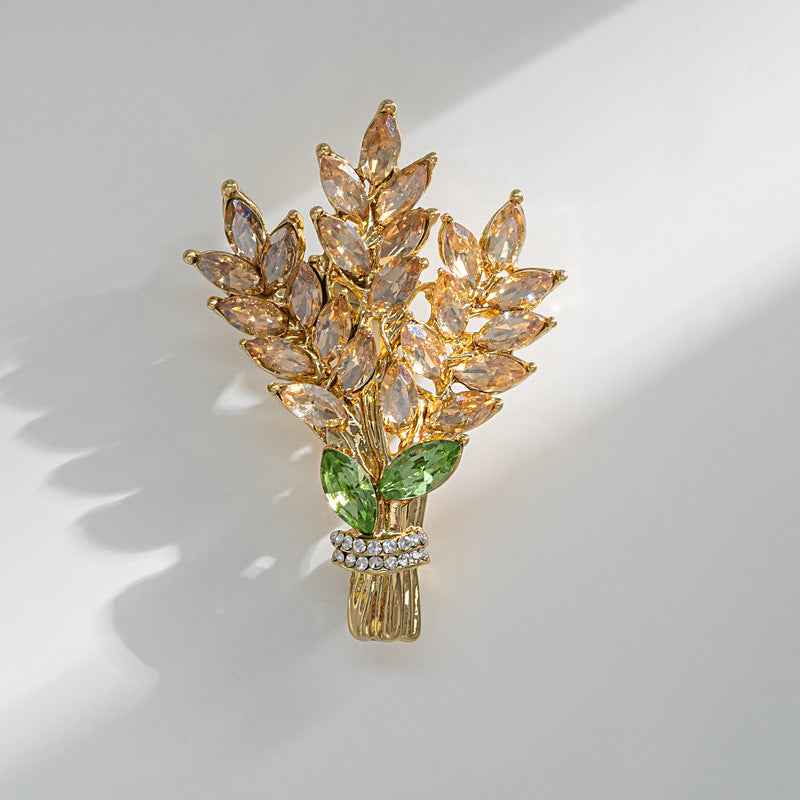 Gold-toned crystal flower brooch pin with green leaf and pavé band