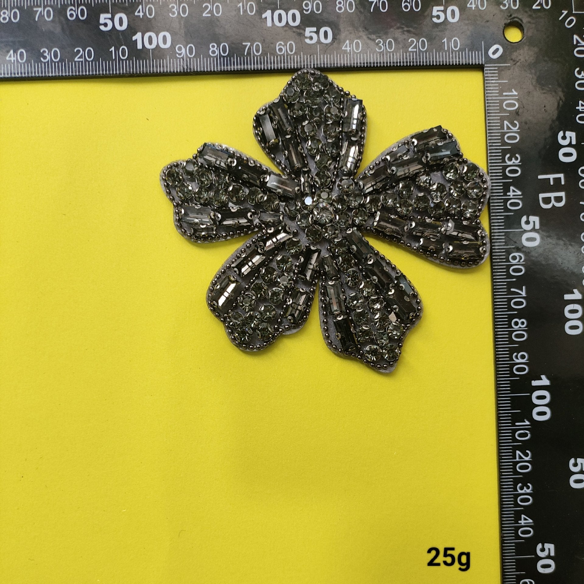 Dark silver bead flower patch with stitched crystal pattern and central sparkle, ruler shown