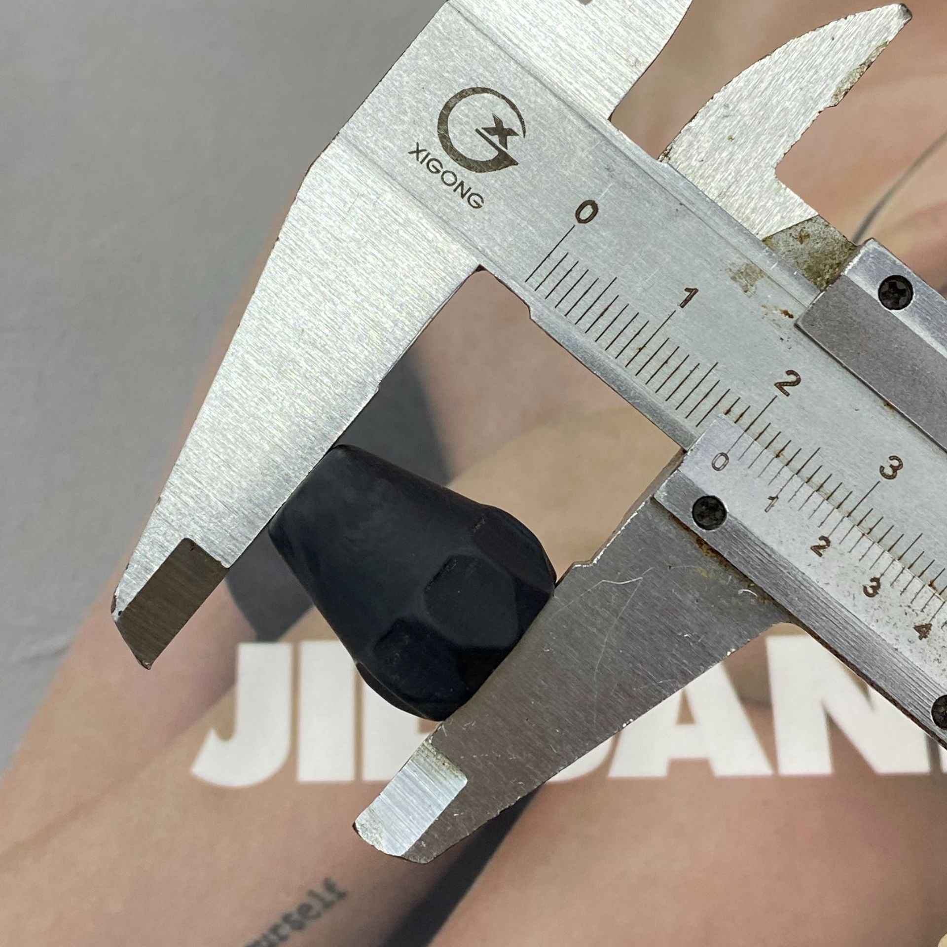 Black resin single-hole cord end stopper measured with calipers