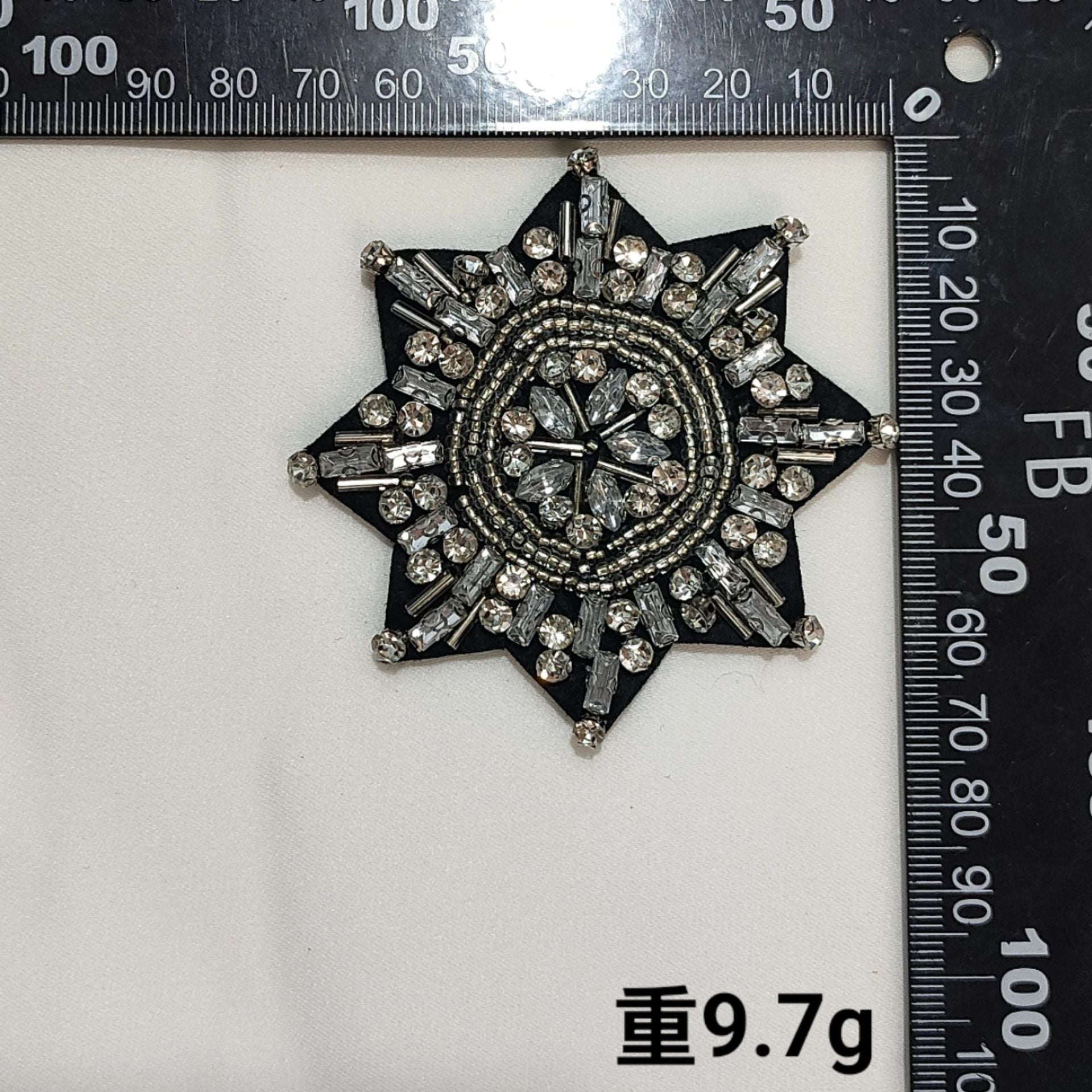 Black fabric starburst badge patch with clear rhinestones and round beaded centerpiece