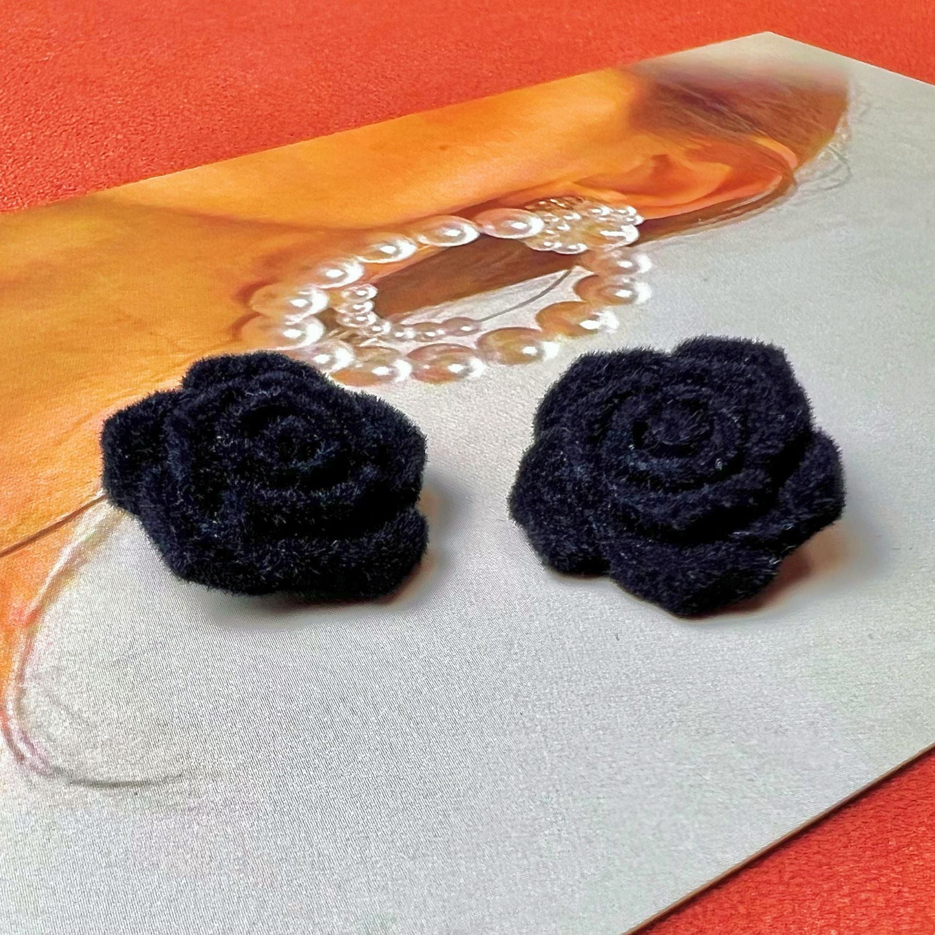 Three dark plush rose buttons on white fabric