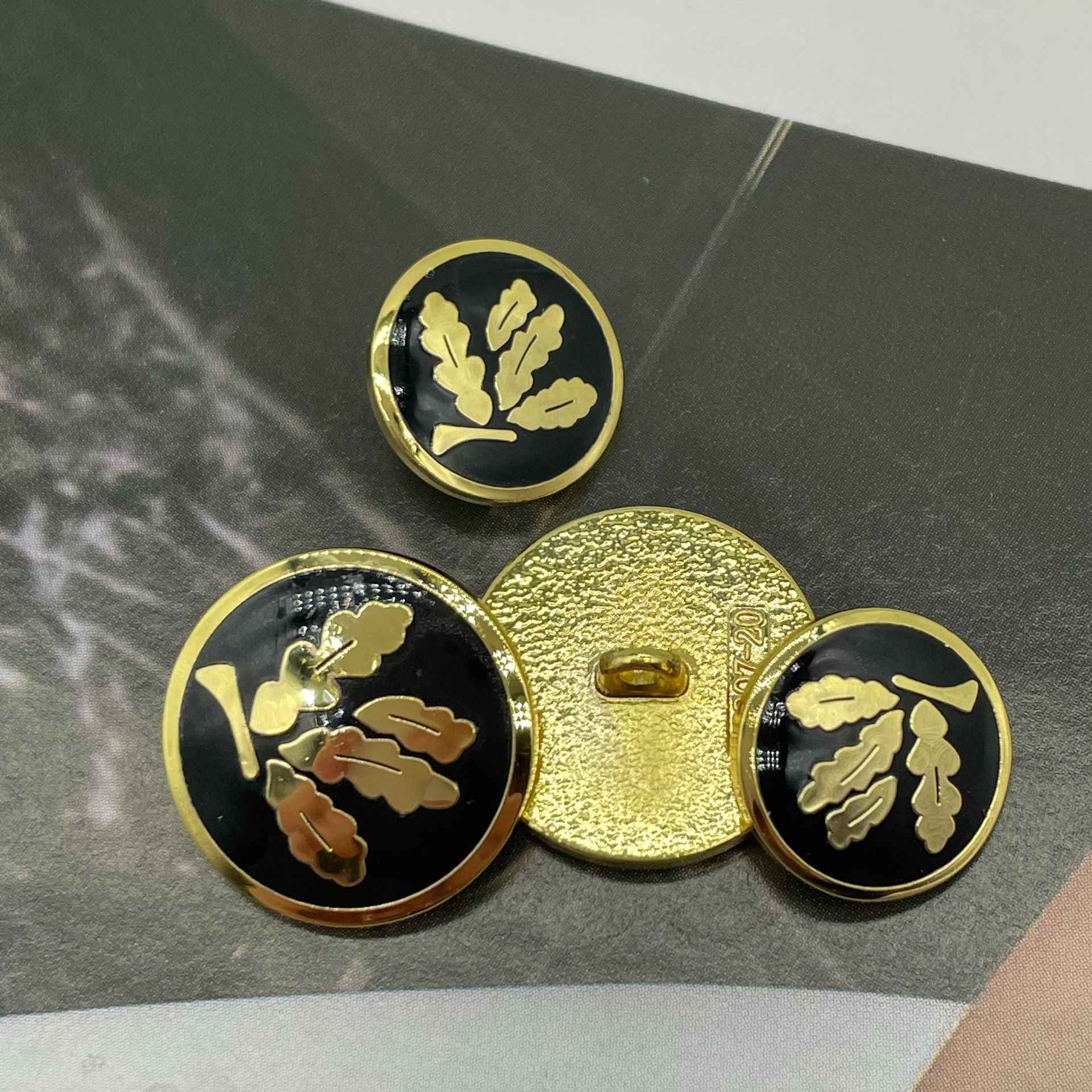 Round buttons with gold shank backs; black fronts with gold leaf motif (3 shown)