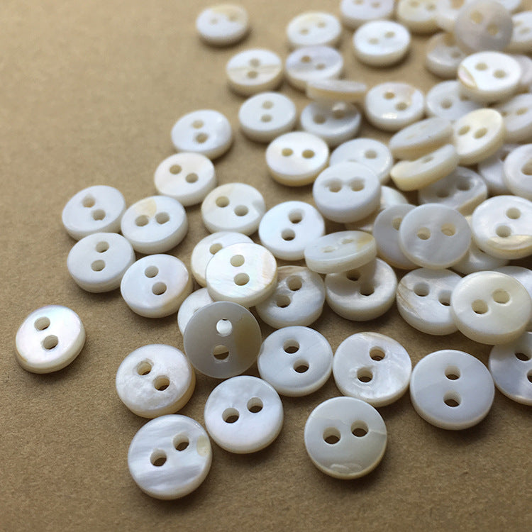 Close-up of natural white mini round shell buttons with two holes (40 pcs)