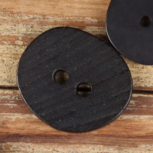 Dark natural 2-hole button with two holes, irregular round shape, close-up.