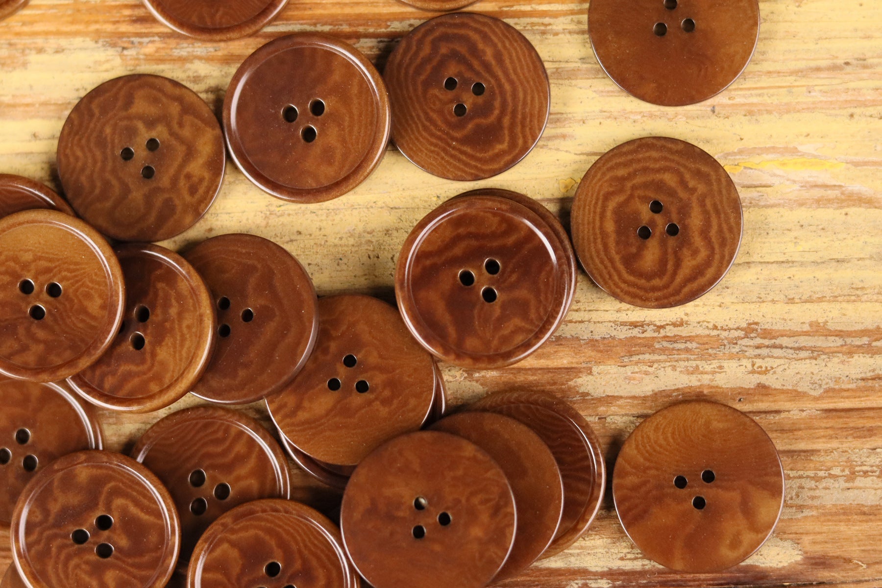 Assorted brown round 3-hole palm nut buttons with thin rim on wood