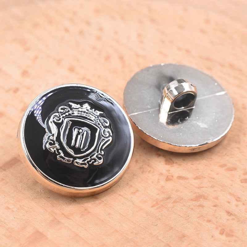 Black 21/23mm plastic shank button front with shield-style engraving and silver rim