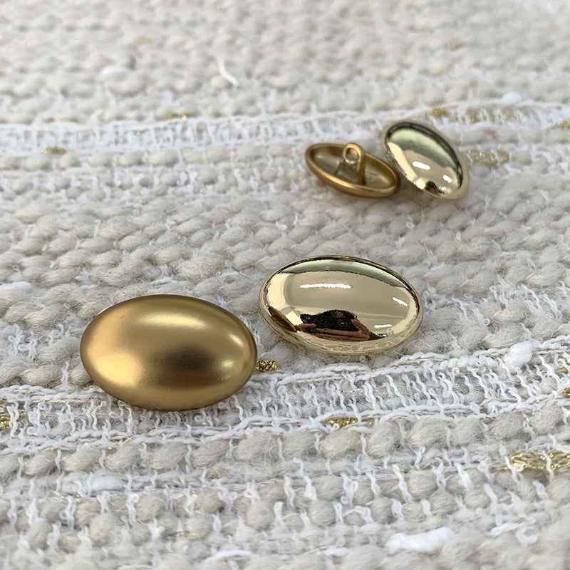 Oval light gold alloy shank buttons showing reflective front and metal shank backs