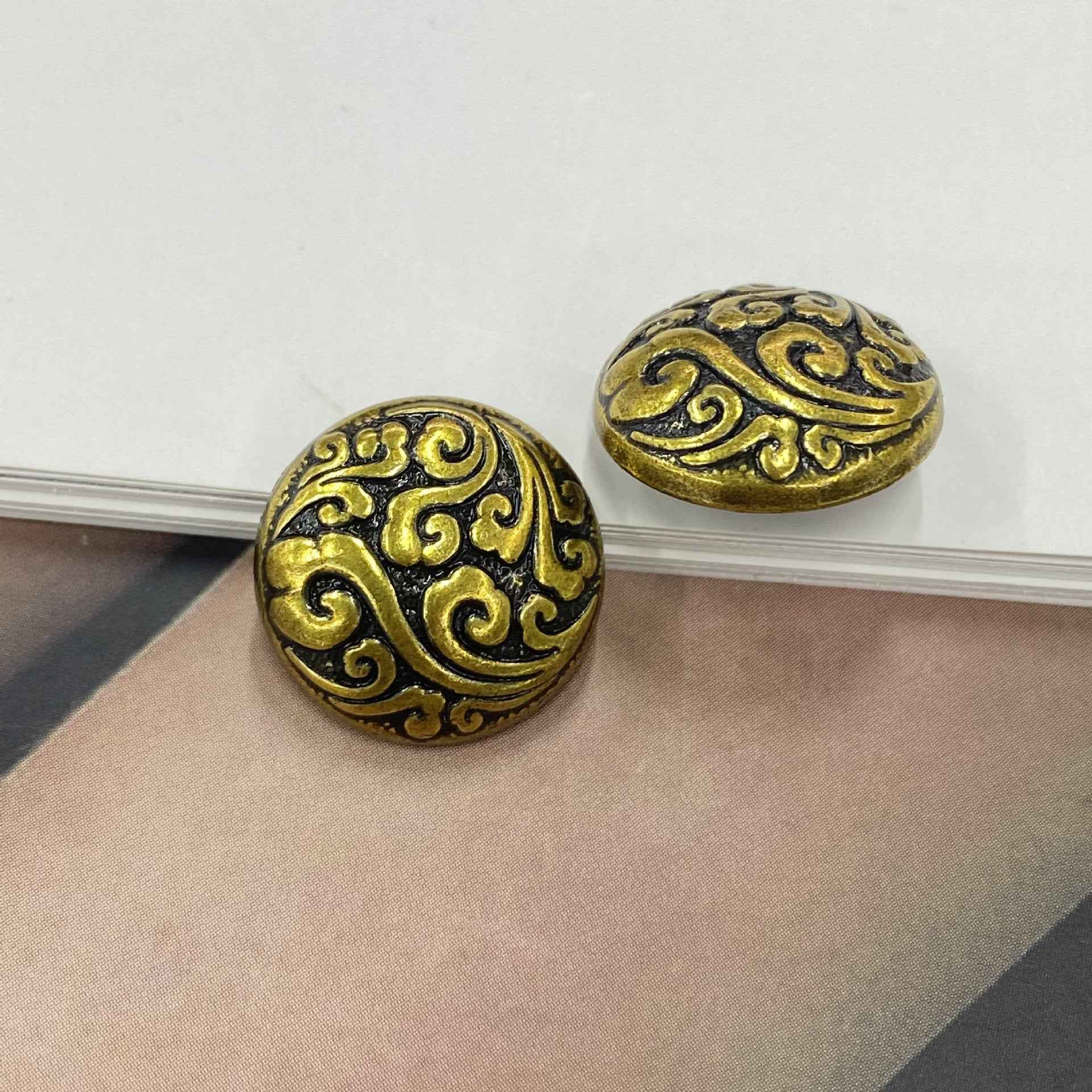 Pair of ornate cloud-pattern metal shank buttons, gold and dark bronze tones, round