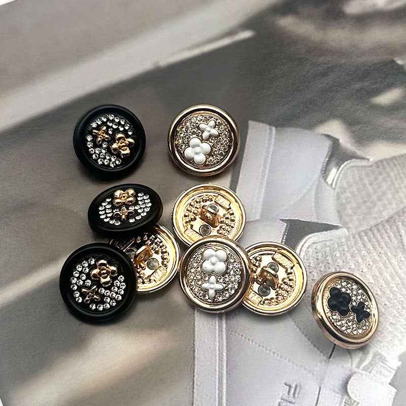 Round two-tone sewing buttons, black faces with gold edging and rhinestone floral pattern